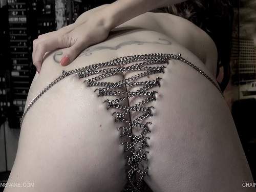 Iron chain penetrates the many piercing rings on pussy